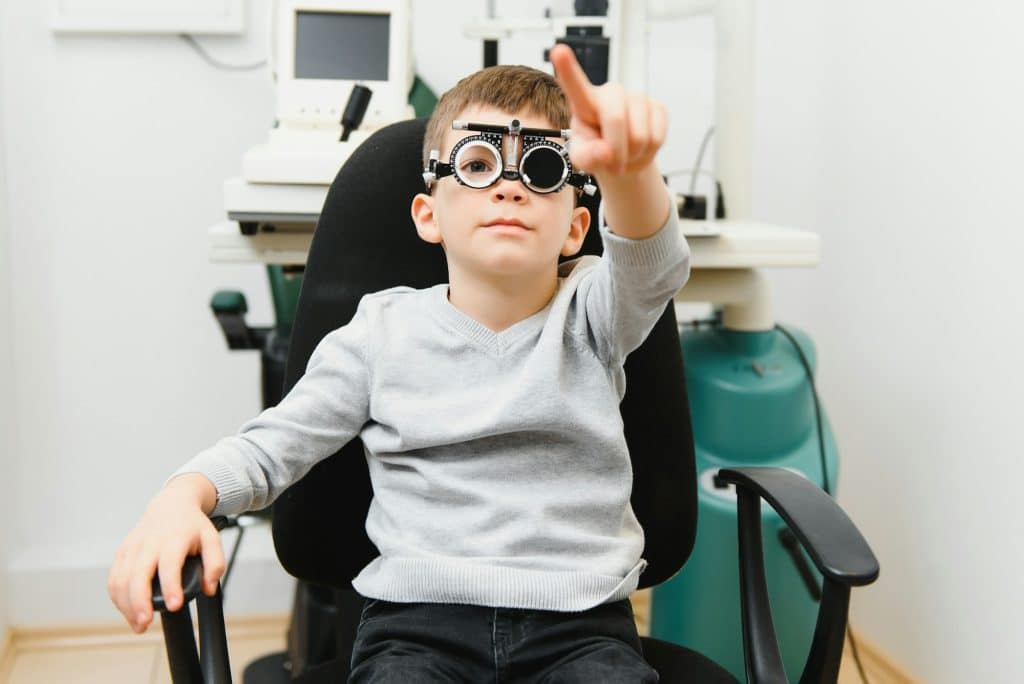 Cheerful child boy in glasses checks eye vision pediatric ophthalmologist