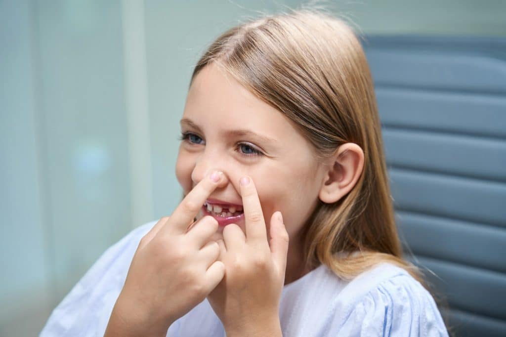 Cheerful pediatric patient learning to put in corrective lenses