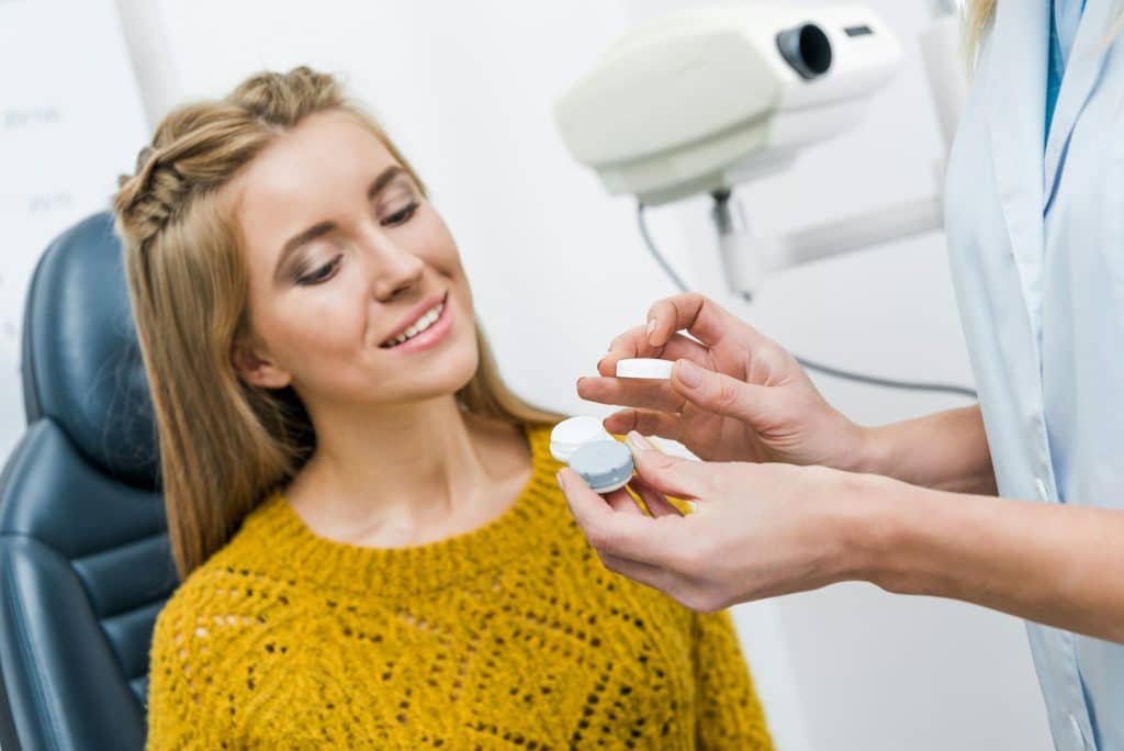 patient and optician with contact lens in clinic