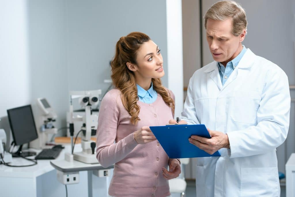 patient looking at ophthalmologist with clipboard in clinic