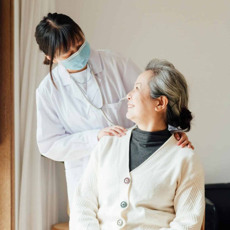 Senior woman with young female doctor at home